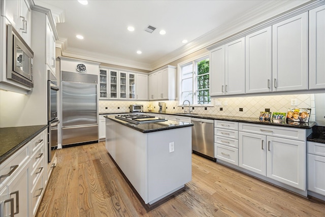 40 E Broad Oaks Dr, Houston, TX 77056 - kitchen with built in appliances, a sink, ornamental molding, a center island, and dark stone counters