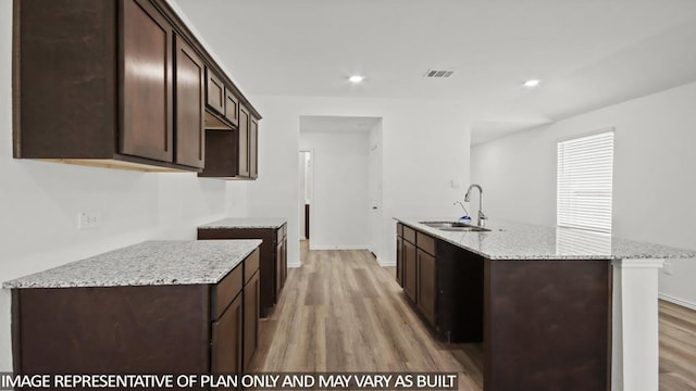 5414 Magnolia Heath Ln, Spring, TX 77373 - kitchen with a sink, light wood-style flooring, dark brown cabinetry, a center island with sink, and recessed lighting