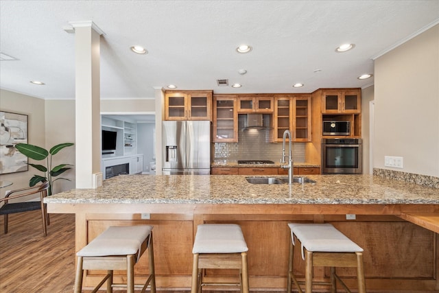 2207 Latexo Dr, Houston, TX 77018 - kitchen featuring stainless steel appliances, a sink, brown cabinets, ornamental molding, and light stone countertops