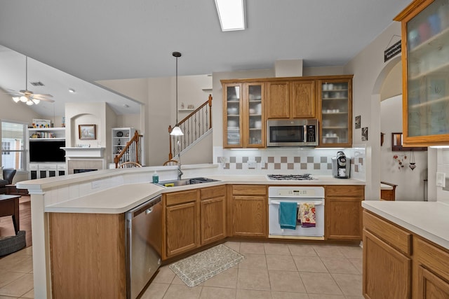 2615 Crystal Falls Dr, Pearland, TX 77584 - kitchen with appliances with stainless steel finishes, a peninsula, open floor plan, a tile fireplace, and light countertops
