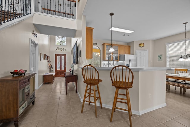 2615 Crystal Falls Dr, Pearland, TX 77584 - kitchen featuring stainless steel fridge with ice dispenser, a chandelier, light tile patterned floors, a breakfast bar, and a towering ceiling