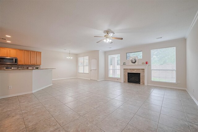 2938 Intrepid Elm St, Houston, TX 77084 - unfurnished living room featuring light tile patterned floors, ceiling fan, a tiled fireplace, baseboards, and ornamental molding