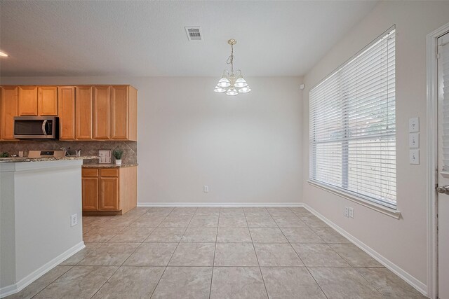 2938 Intrepid Elm St, Houston, TX 77084 - kitchen with stainless steel microwave, backsplash, a chandelier, light stone counters, and pendant lighting