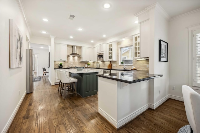 2621 Morrison St, Houston, TX 77009 - kitchen featuring wall chimney exhaust hood, a breakfast bar, appliances with stainless steel finishes, decorative backsplash, and crown molding