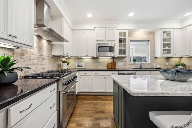 2621 Morrison St, Houston, TX 77009 - kitchen with stainless steel appliances, wall chimney exhaust hood, a sink, ornamental molding, and white cabinets