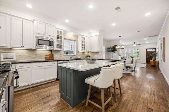2621 Morrison St, Houston, TX 77009 - kitchen with stainless steel appliances, a sink, a breakfast bar area, backsplash, and a kitchen island