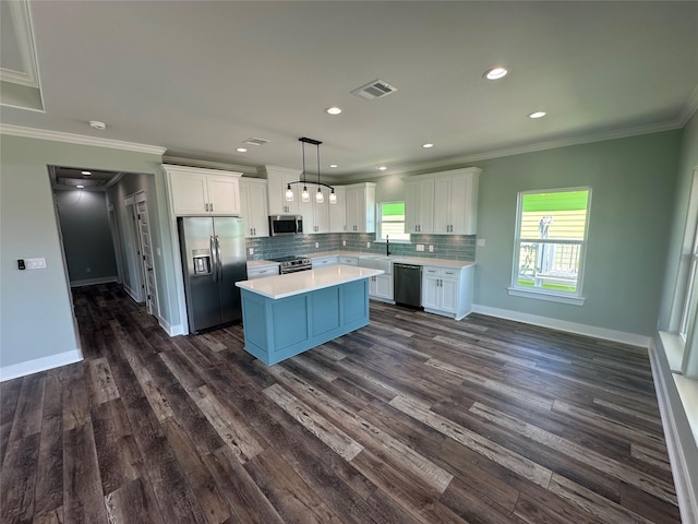 969 Bahama Rd, Crystal Beach, TX 77650 - kitchen with stainless steel appliances, ornamental molding, light countertops, white cabinetry, and decorative backsplash