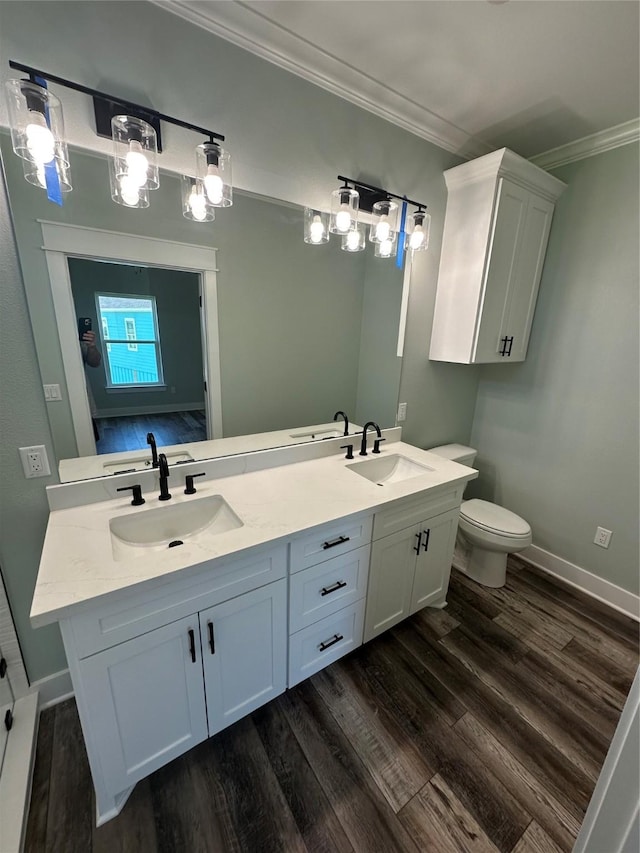 969 Bahama Rd, Crystal Beach, TX 77650 - bathroom with wood finished floors, crown molding, double vanity, baseboards, and toilet