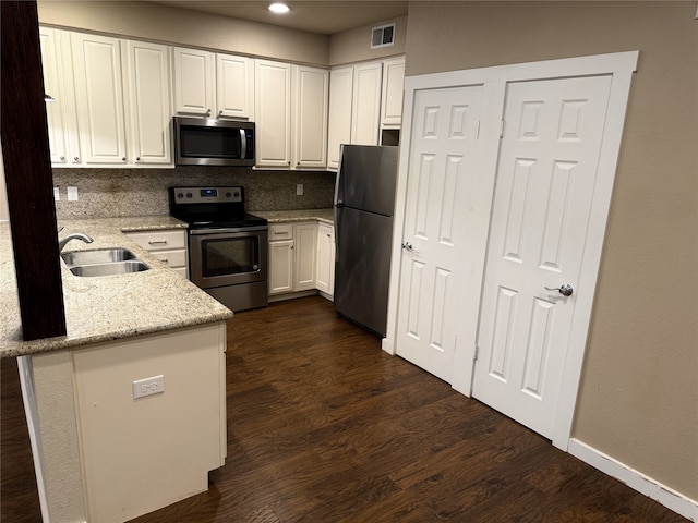 87 April Point Dr S, Conroe, TX 77356 - kitchen with appliances with stainless steel finishes, a sink, white cabinetry, dark wood-style flooring, and tasteful backsplash