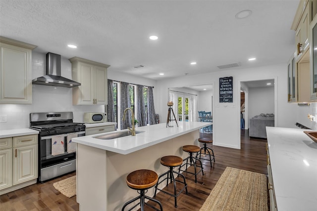 1710 Hill Top Ln, Houston, TX 77339 - kitchen featuring wall chimney range hood, gas stove, a sink, white microwave, and cream cabinets