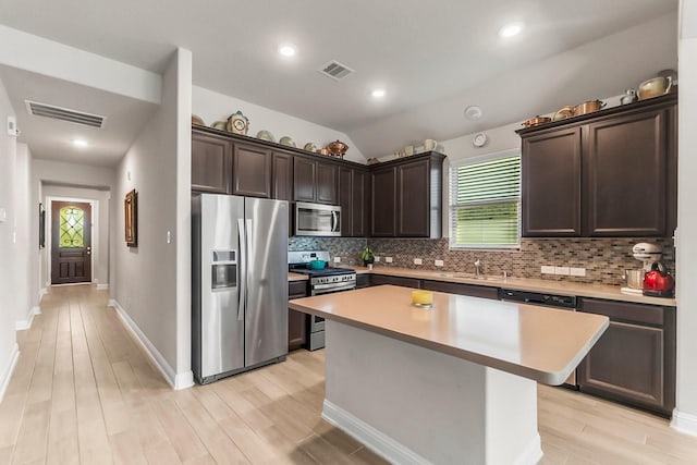 8202 Lockridge Terrace Ln, Cypress, TX 77433 - kitchen featuring appliances with stainless steel finishes, dark brown cabinets, tasteful backsplash, a kitchen island, and light wood finished floors