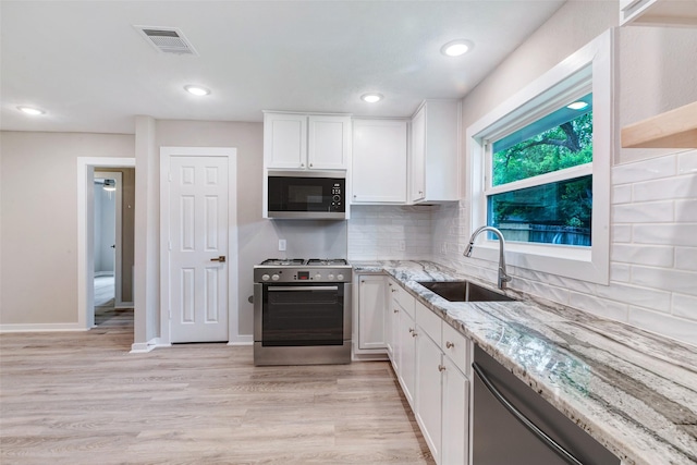 5858 Beldart St, Houston, TX 77033 - kitchen with appliances with stainless steel finishes, a sink, light stone counters, white cabinetry, and recessed lighting
