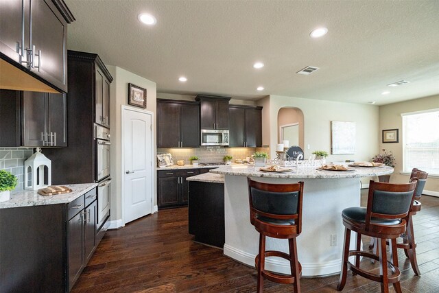 27619 Dalton Bluff Ct, Katy, TX 77494 - kitchen featuring appliances with stainless steel finishes, a kitchen island, dark wood-style flooring, decorative backsplash, and recessed lighting
