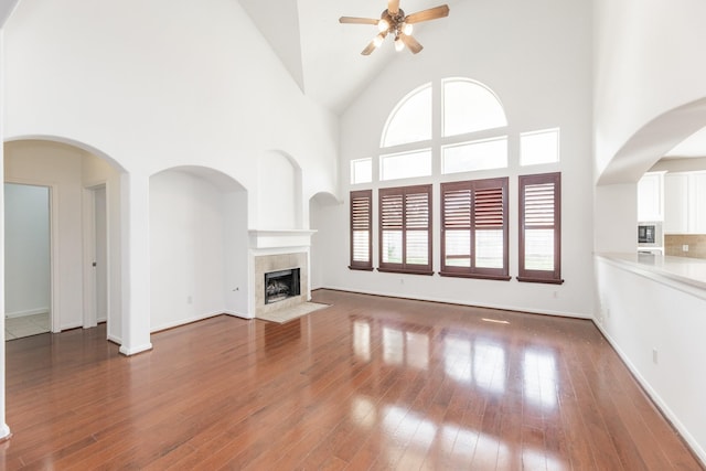 3604 Dogwood Blossom Ct, Pearland, TX 77581 - unfurnished living room with ceiling fan, high vaulted ceiling, a tile fireplace, wood-type flooring, and baseboards