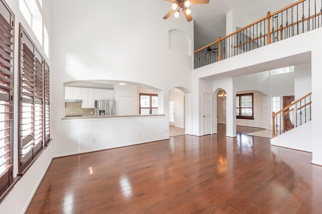 3604 Dogwood Blossom Ct, Pearland, TX 77581 - unfurnished living room with a high ceiling, ceiling fan, wood finished floors, stairway, and arched walkways