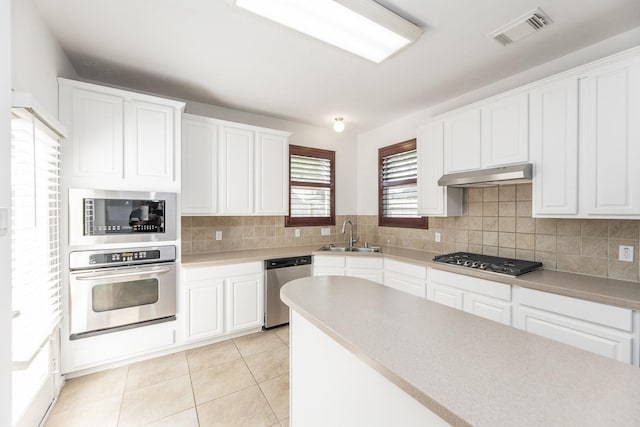 3604 Dogwood Blossom Ct, Pearland, TX 77581 - kitchen with appliances with stainless steel finishes, a sink, under cabinet range hood, backsplash, and white cabinetry