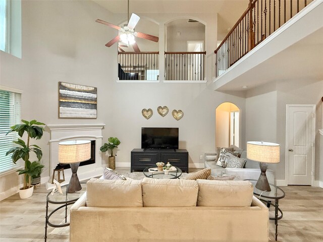 210 Black Swan Pl, The Woodlands, TX 77354 - living area featuring arched walkways, a towering ceiling, wood finished floors, ceiling fan, and baseboards