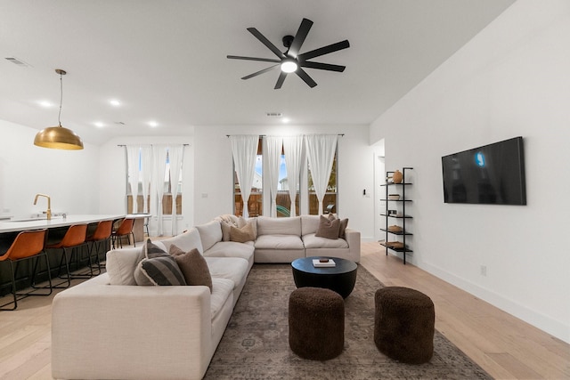 17460 Chestnut Cove Dr, Conroe, TX 77302 - living area featuring light wood-type flooring, a ceiling fan, bar with sink, and baseboards