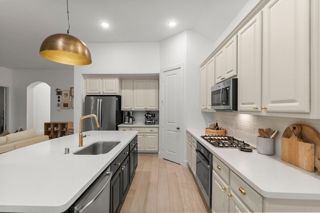 17460 Chestnut Cove Dr, Conroe, TX 77302 - kitchen with stainless steel appliances, a sink, arched walkways, light countertops, and tasteful backsplash
