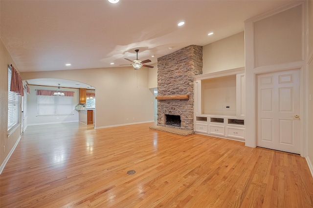 2718 Silver Falls Dr, Kingwood, TX 77339 - unfurnished living room featuring a fireplace, light wood-type flooring, ceiling fan, arched walkways, and recessed lighting