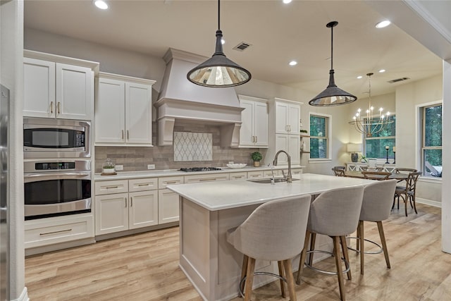 130 Playmoor Pl, Montgomery, TX 77316 - kitchen featuring stainless steel appliances, a sink, backsplash, light countertops, and light wood-style flooring