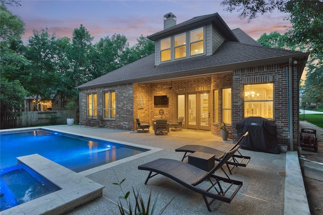 130 Playmoor Pl, Montgomery, TX 77316 - back of house with brick siding, a chimney, a patio, roof with shingles, and an in-ground hot tub