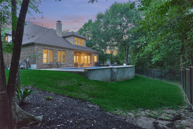 130 Playmoor Pl, Montgomery, TX 77316 - back of house at dusk featuring brick siding, a chimney, and a shingled roof