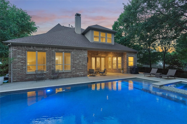 130 Playmoor Pl, Montgomery, TX 77316 - back of house featuring brick siding, a pool with connected hot tub, a patio, and a chimney
