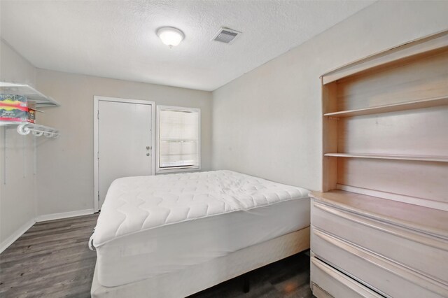 603 Briarwood Dr, Baytown, TX 77520 - bedroom with dark wood-style flooring, a textured ceiling, and baseboards
