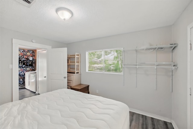 603 Briarwood Dr, Baytown, TX 77520 - bedroom with dark wood-type flooring, a textured ceiling, baseboards, and washer / clothes dryer