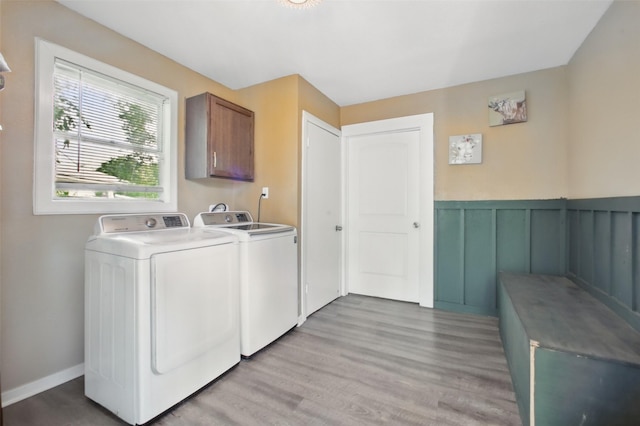 603 Briarwood Dr, Baytown, TX 77520 - laundry room featuring washing machine and dryer, light wood-style floors, a wainscoted wall, and cabinet space