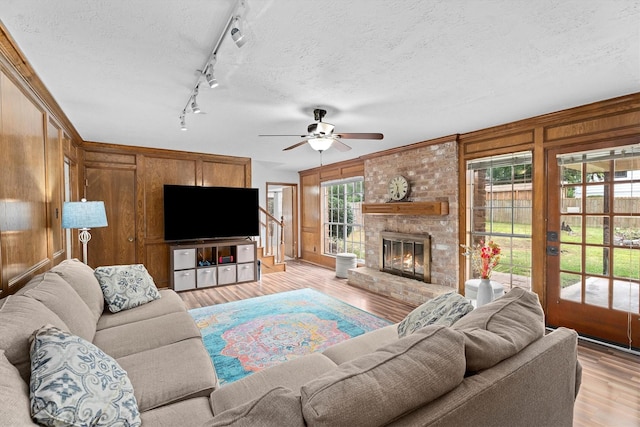 819 Maranon Ln, Houston, TX 77090 - living room with light wood-style floors, a ceiling fan, a textured ceiling, track lighting, and a brick fireplace