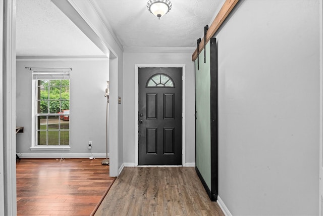 819 Maranon Ln, Houston, TX 77090 - entryway with wood finished floors, a barn door, ornamental molding, baseboards, and a textured ceiling