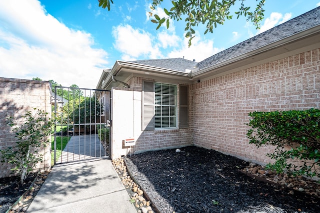 51 Eagle Mead Pl, The Woodlands, TX 77382 - view of home's exterior with brick siding, a gate, and a shingled roof