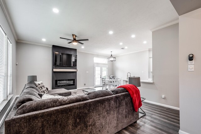 51 Eagle Mead Pl, The Woodlands, TX 77382 - living room with dark wood-type flooring, a large fireplace, baseboards, ornamental molding, and ceiling fan