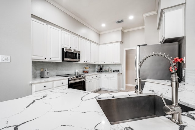 51 Eagle Mead Pl, The Woodlands, TX 77382 - kitchen featuring appliances with stainless steel finishes, ornamental molding, a sink, decorative backsplash, and white cabinets