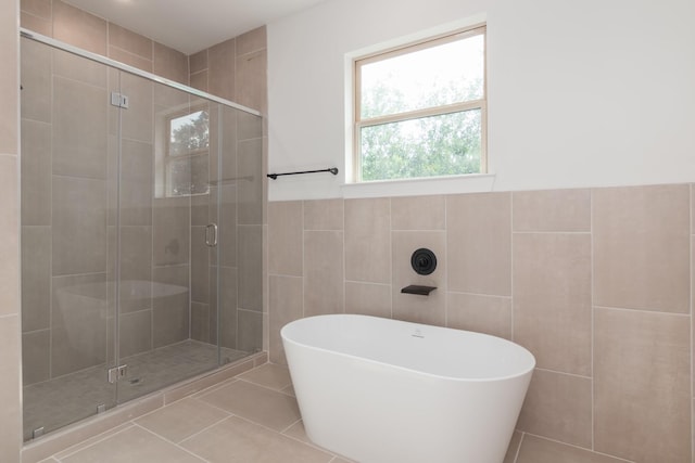 1411 E 34th St, Houston, TX 77022 - bathroom featuring a shower stall, a soaking tub, tile patterned floors, tile walls, and wainscoting