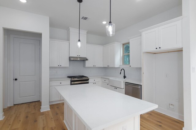 1411 E 34th St, Houston, TX 77022 - kitchen with appliances with stainless steel finishes, a sink, under cabinet range hood, light wood-type flooring, and recessed lighting