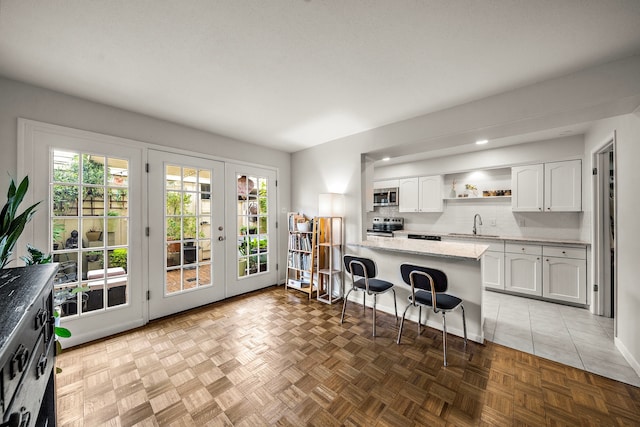 6417 Olympia Dr Unit 144, Houston, TX 77057 - kitchen featuring appliances with stainless steel finishes, open shelves, a breakfast bar, white cabinets, and plenty of natural light