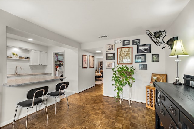 6417 Olympia Dr Unit 144, Houston, TX 77057 - kitchen featuring white cabinetry, baseboards, open shelves, a breakfast bar, and a sink