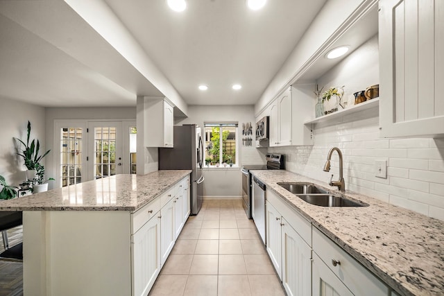 6417 Olympia Dr Unit 144, Houston, TX 77057 - kitchen with a sink, appliances with stainless steel finishes, white cabinets, backsplash, and a peninsula