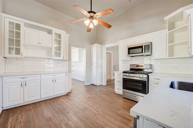 1318 Bingham St, Houston, TX 77007 - kitchen featuring appliances with stainless steel finishes, open shelves, ceiling fan, backsplash, and white cabinets