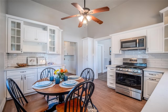 1318 Bingham St, Houston, TX 77007 - kitchen featuring appliances with stainless steel finishes, open shelves, light countertops, white cabinetry, and a high ceiling