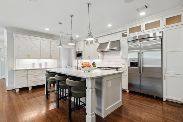 1409 Tulane St, Houston, TX 77008 - kitchen with built in appliances, under cabinet range hood, white cabinets, backsplash, and light stone counters