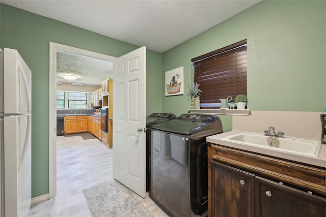 517 Hillebrandt, Beaumont, TX 77705 - laundry area featuring a textured ceiling, washing machine and clothes dryer, and light wood-style flooring