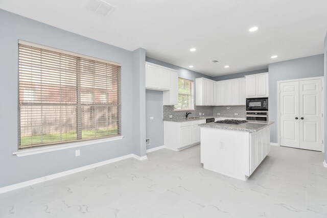 19 Long Springs Pl, The Woodlands, TX 77382 - kitchen with stainless steel appliances, white cabinets, backsplash, a sink, and baseboards