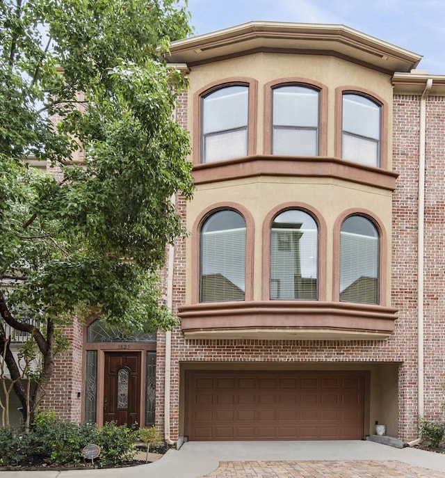 1825 Stanford St, Houston, TX 77006 - view of property featuring an attached garage, driveway, brick siding, and stucco siding