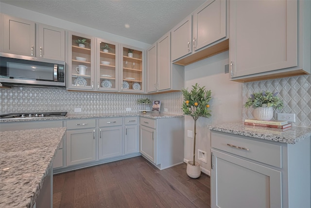 2923 Laurel Mill Way, Houston, TX 77080 - kitchen featuring appliances with stainless steel finishes, dark wood-type flooring, decorative backsplash, glass insert cabinets, and light stone countertops