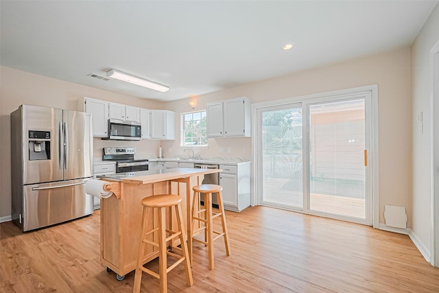 115 N 12th St, Highlands, TX 77562 - kitchen with stainless steel appliances, a breakfast bar, light countertops, light wood finished floors, and recessed lighting