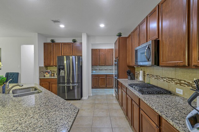 28614 Cabrera Hill Ln, Katy, TX 77494 - kitchen with stainless steel appliances, a sink, decorative backsplash, light stone counters, and light tile patterned floors